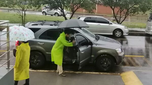 Profes reciben a sus alumnos con paraguas para que no se mojen