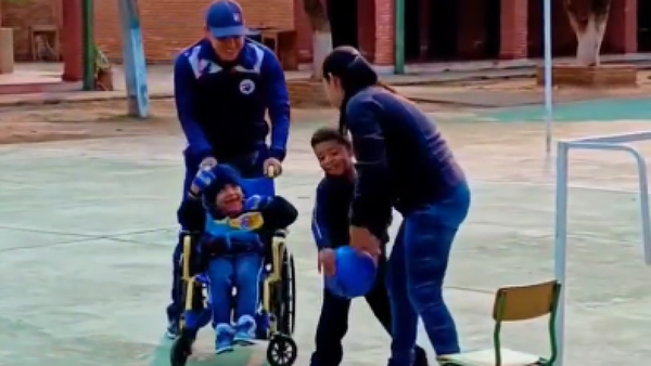Docente emociona al ayudar a alumno en silla de ruedas a jugar con sus compañeros