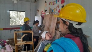 Al amparo de su recién nacida, una madre fabrica la puerta de su casa